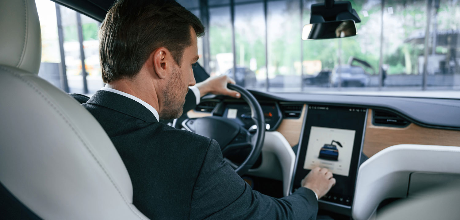 Rear view of a driver in an electric car using advanced driver-assistance, illustrating AI-powered vehicle crash liability in New York City.