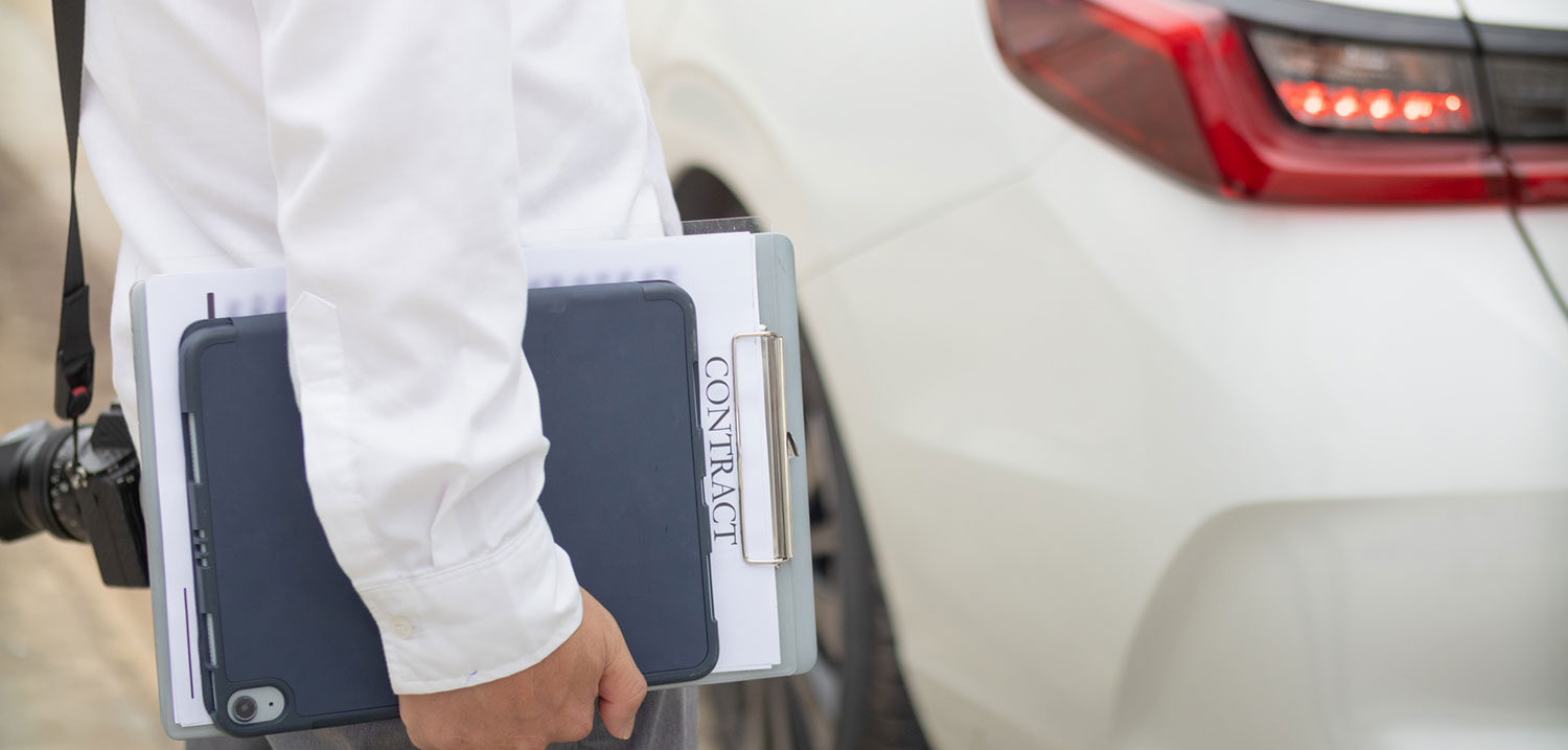 Insurance agent inspecting a damaged car with the owner after a crash, illustrating Long Island car accident claims and legal help.
